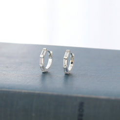 Silver-tone crystal huggie hoops on linen