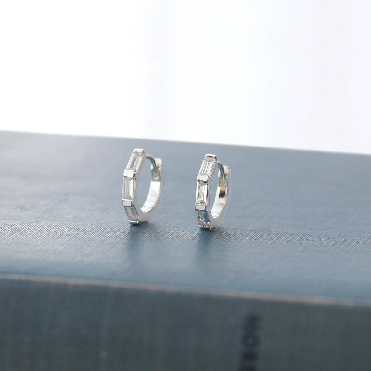 Silver-tone crystal huggie hoops on linen