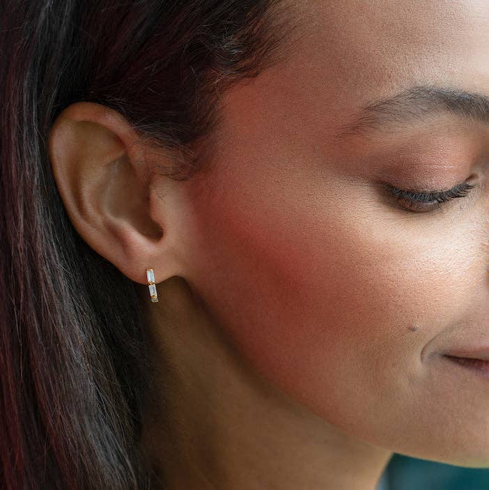 Small gold hoops with crystal baguettes worn on the ear