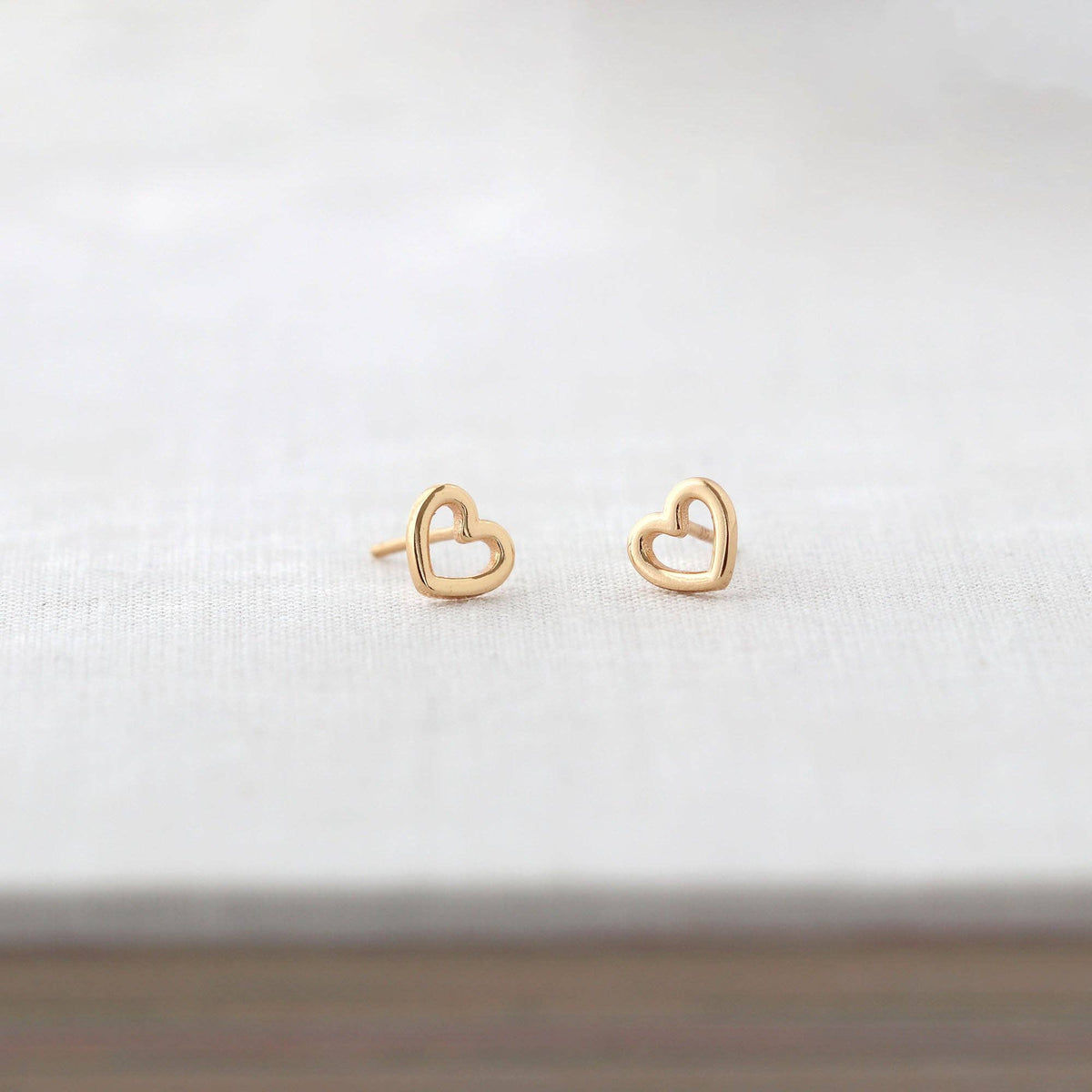 Heart Outline Stud Earrings in gold vermeil laid on linen