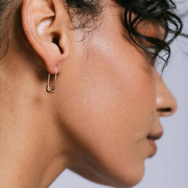 Silver safety pin hoop in an ear stack with studs and an ear cuff
