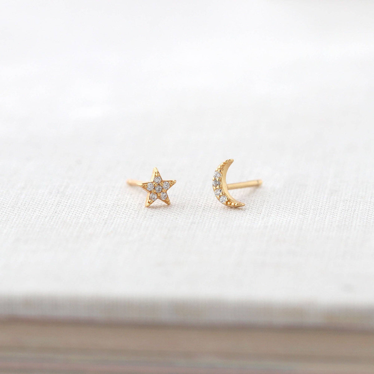Star and Moon Crystal Stud Earrings in gold vermeil on a white book