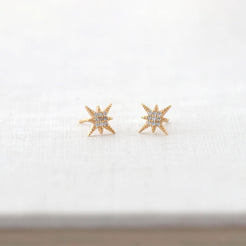 Starburst Crystal Stud Earrings in gold vermeil resting on a white book