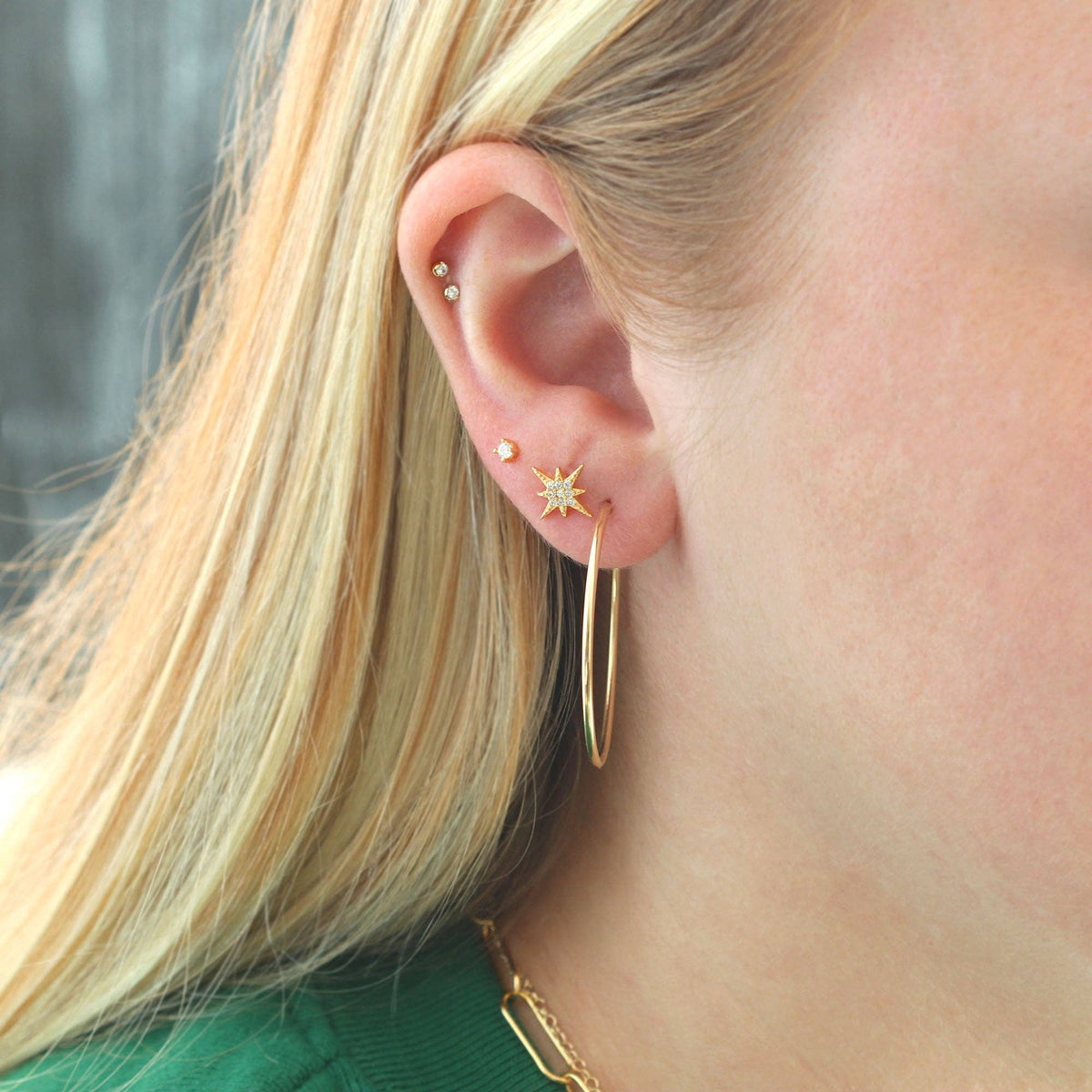 Woman with dark hair wearing small gold starburst studs