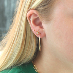 Woman with dark hair wearing small gold starburst studs